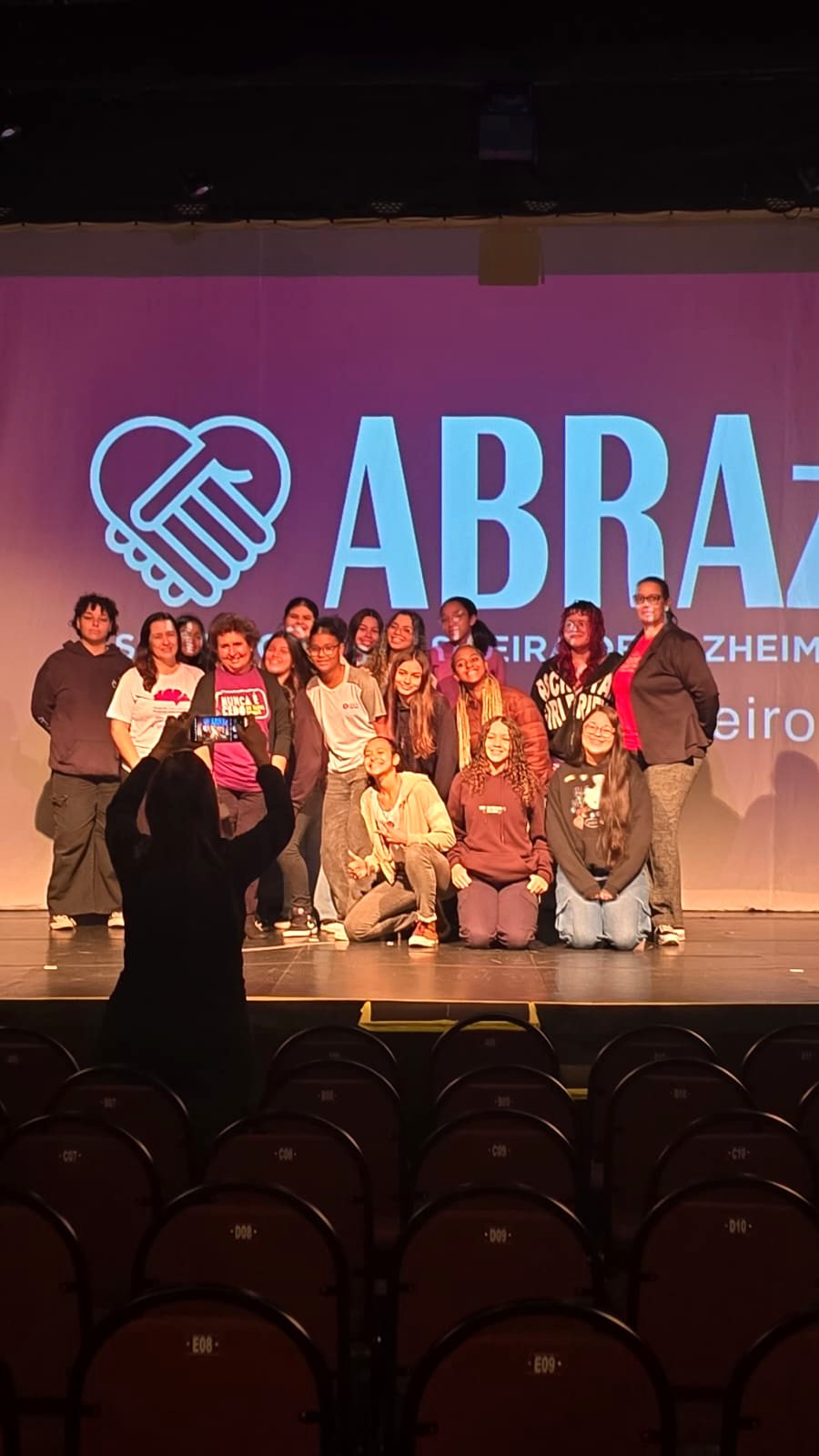 Participantes reunidos no palco para a foto final, diante do painel da ABRAz