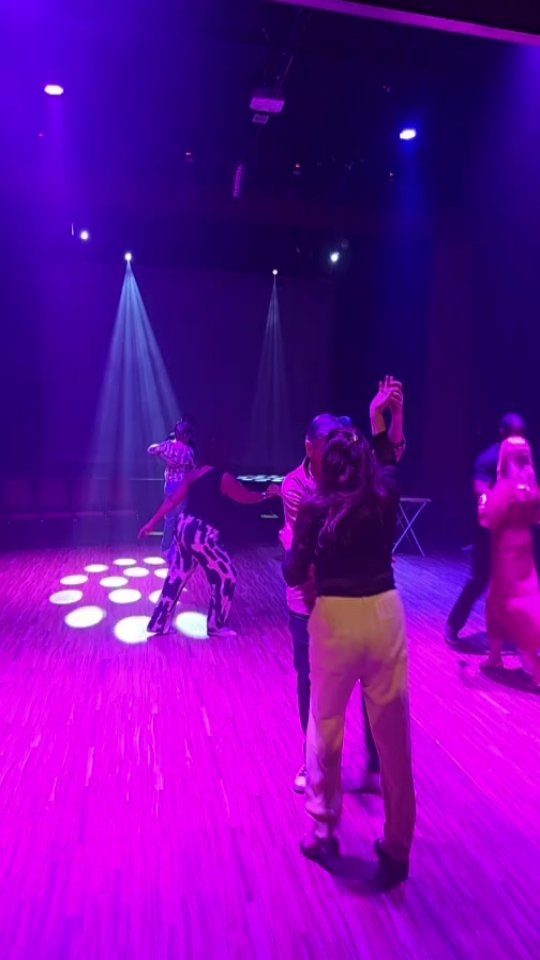 Casais dançando no palco iluminado do Espaço Cultural Panorama