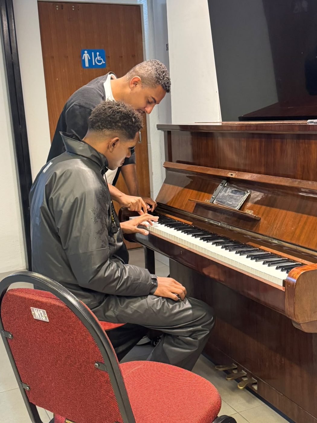 Professor mostrando a posição das mãos no teclado do piano